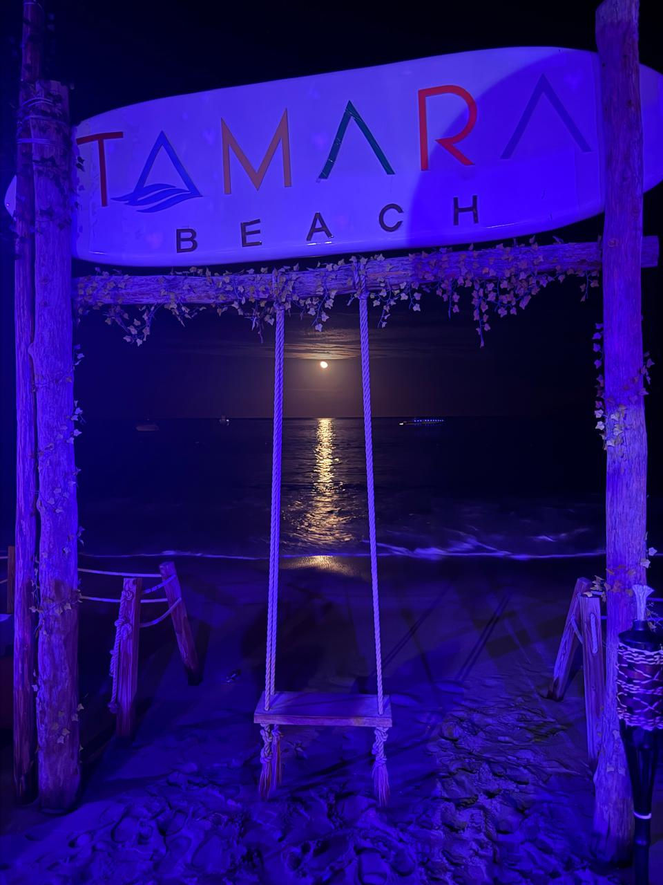 Full moon over the ocean behind the Tamara Beach Club swing in Los Cabos